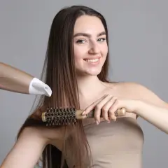 Kobieta suszy i modeluje włosy okrągłą szczotką i suszarką.