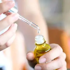 Kropla serum z kwasem laktobionowym spada z pipety do małej, żółtej buteleczki.