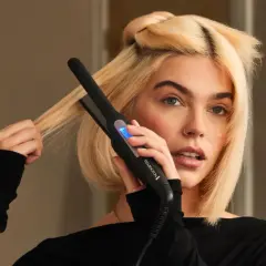 Blondynka używa prostownicy Remington, by nadać objętość włosom u nasady.
