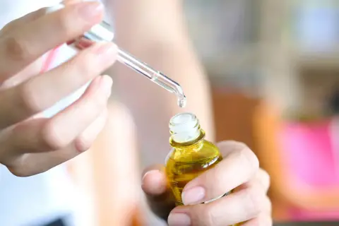 Kropla serum z kwasem laktobionowym spada z pipety do małej, żółtej buteleczki.
