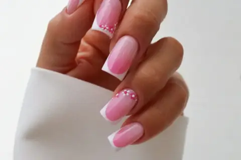 Delikatny french manicure z różowym ombre i ozdobnymi kwiatuszkami. Idealny pomysł, czym zrobić french, by wyglądał subtelnie i kobieco.